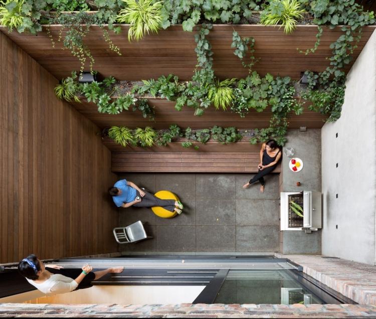 terrasseengestaltung-innenhof-betonfliesen-outdoor-grill-holz-sitzbank-hochbeete-pflanzen
