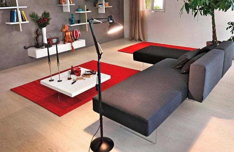 Sofa-Grau-rot-Teppich-Wandregal-weiss-Stehlampe