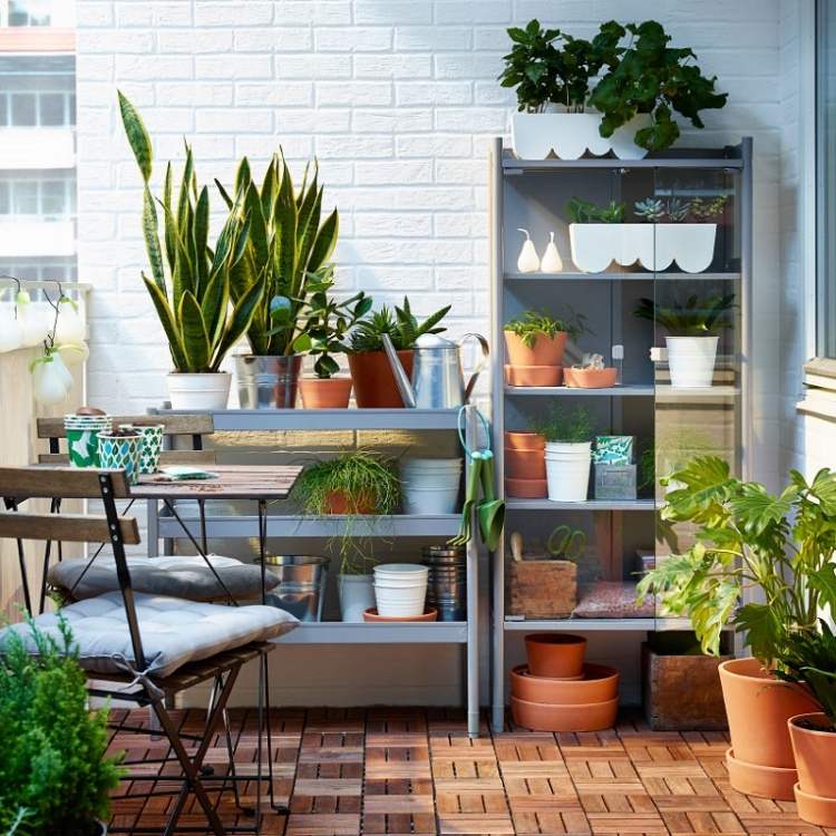 balkon-fliesen-holz-praktische-regale-outdoor-klappstuehle-pflanzen-pflanztisch-backsteinwand-weiss-gestrichen