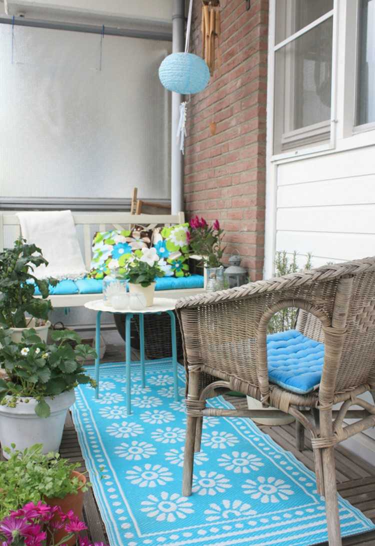 balkon-gestalten-tipps-holz-bodenbelag-blauer-outdoor-teppich-kunststoffgeflecht-stuhl