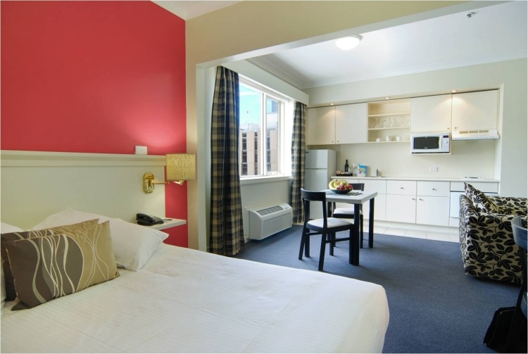 leseleuchte-bett-modern-schlafzimmer-wandfarbe-rot-kuechenzeile-integriert-einzimmerwohnung