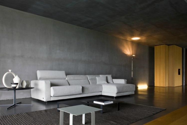 wohnzimmer-grau-eckcouch-wess-betonwand-beleuchtung-teppich-minimalistisches-design