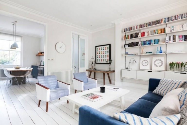 Wohnzimmer in Weiß -samt-blau-dielenboden-geweisst-wohnwand-buecherregale-vintage