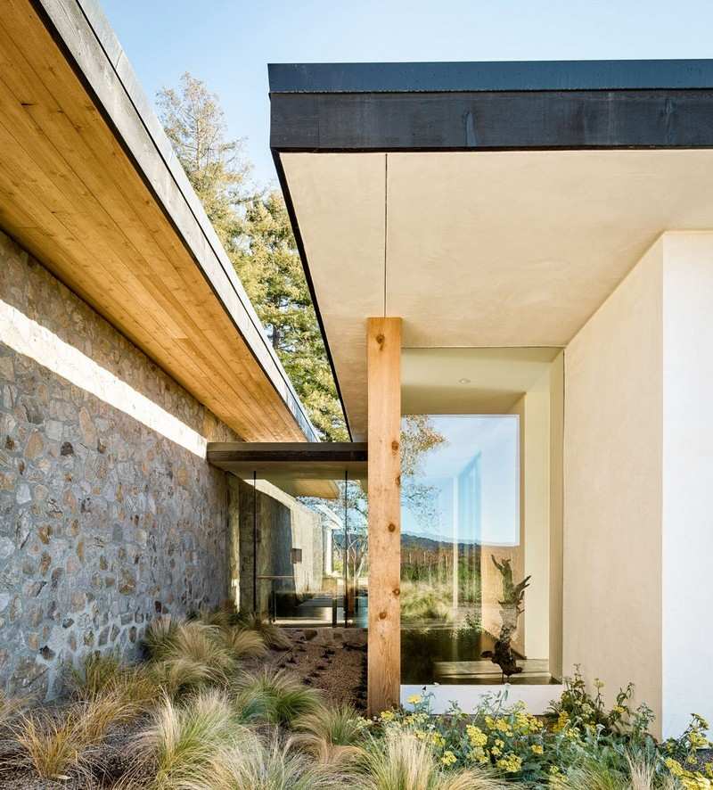 Holz-Naturstein-Fassade-Balken-Ziergraeser-modern
