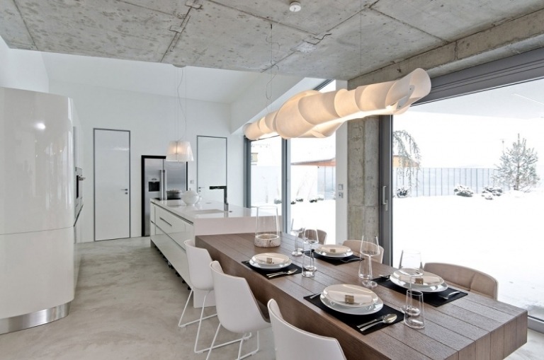 beton-design-modern-esstisch-tischplatte-massivholz-pendelleuchte-stuehle-weiss-fensterfronten-kueche