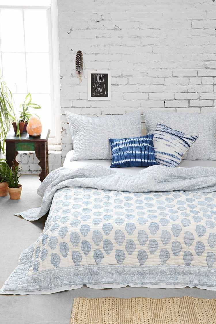 bohemian-style-schlafzimmer-weiss-backsteinwand-bettdecke-blau-laeufer-pflanzen