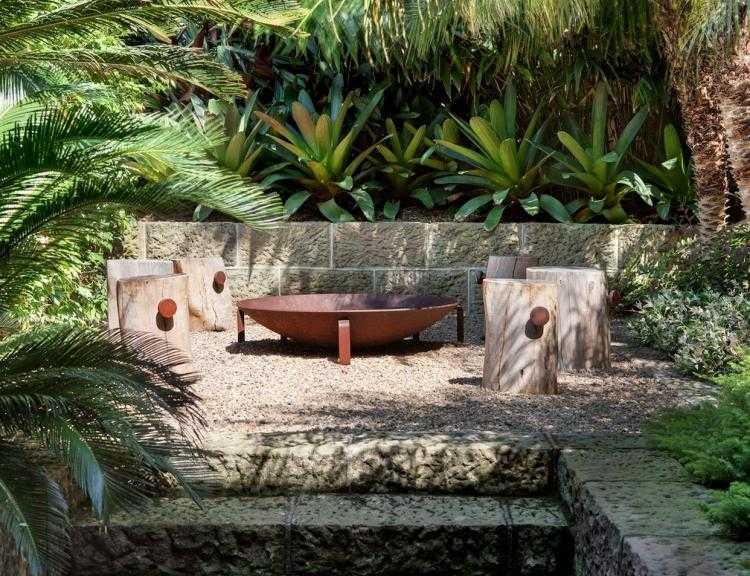 Feuerstelle im Garten -sitzplatz-exotisch-tropisch-naturstein-holz-baumstamm-hocker-cortenstahl