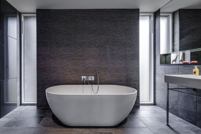 landhaus-stil-moderne-architektur-einrichtung-badezimmer-grau-naturstein-fliesen-freistehende-badewanne-schlicht