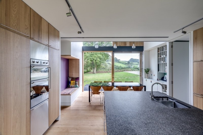 landhaus-stil-moderne-architektur-einrichtung-kueche-holzfronten-granitplatte-grau-holzboden-fensterfront-essbereich