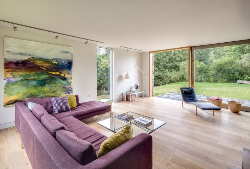 landhaus-stil-moderne-architektur-einrichtung-wohnzimmer-holzboden-eckcouch-violett-polster-bild-verwischte-farben