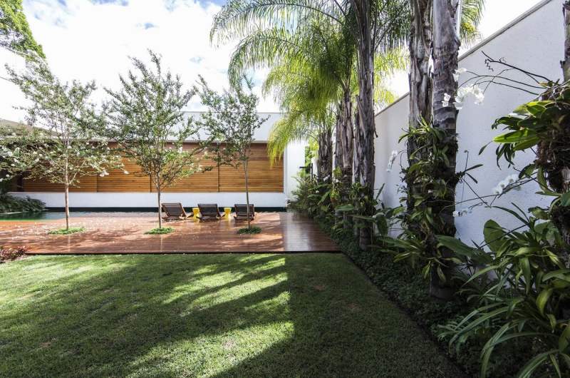 Moderne Gartengestaltung -holzfassade-rasen-palmen-pflanzen-holzboden-pool-liegen