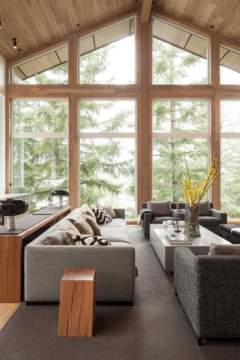 Moderner Landhausstil -umbau-almhaus-wohnzimmer-couch-sessel-grau-polster-vase-couchtisch-fensterfronten