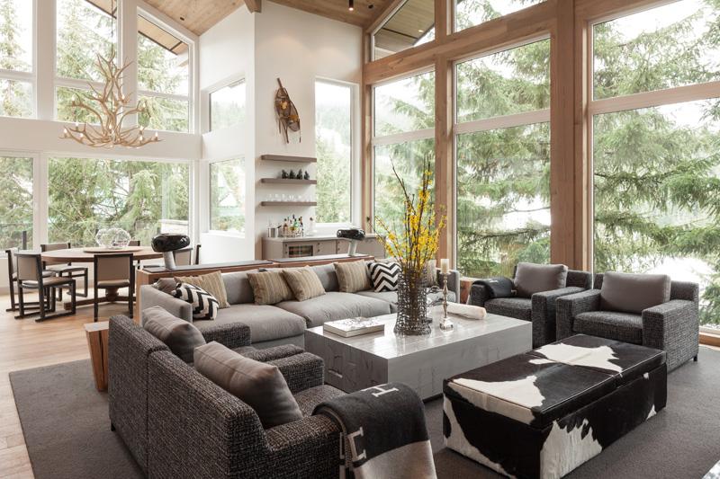 Moderner Landhausstil -umbau-almhaus-wohnzimmer-couch-sessel-grau-wald-fensterronten-vase-couchtisch