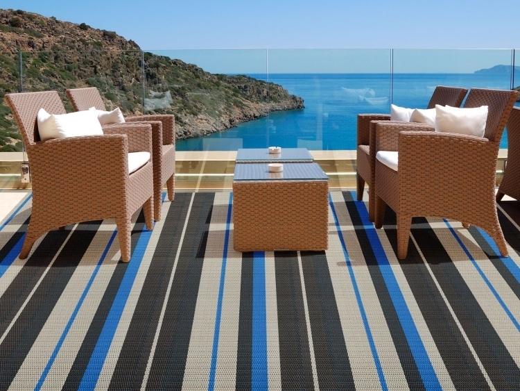 outdoor-teppiche-design-braun-streifen-schwarz-blau-terrasse-aussicht-meer-glasgelaender-kunststoffrattan
