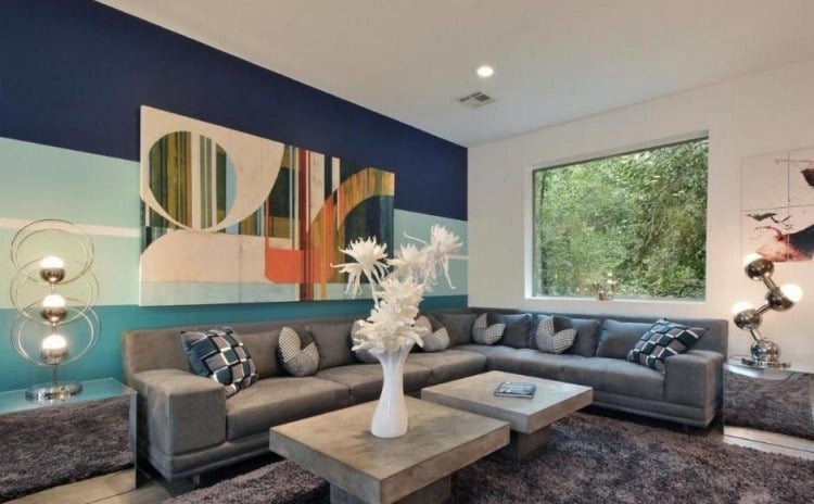 einrichtungsideen-wohnzimmer-gemuetlich-eckcouch-grau-kissen-wandgestaltung-bild-blau-fenster-teppich