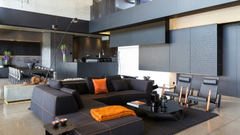 interieur bodenbelag beton schwarz couch orange akzent stuehle teppich