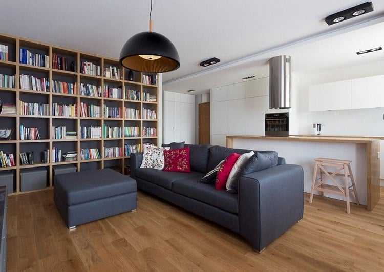 modernes-wohnzimmer-sofa-anthrazit-holzboden-rote-kissen-weisse-wohnkueche