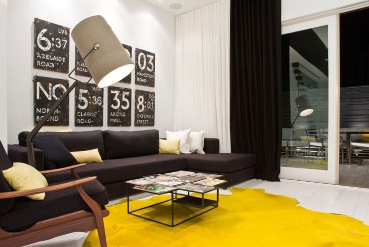 wandgestaltung-schwarz-weiss-wohnzimmer-gelb-teppich-strahler-industrial-design-bilderwand