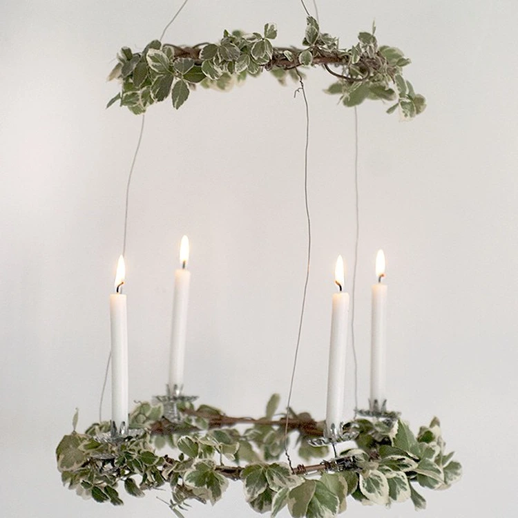 minimalistischer kranz aus frischem grün und weißen kerzen