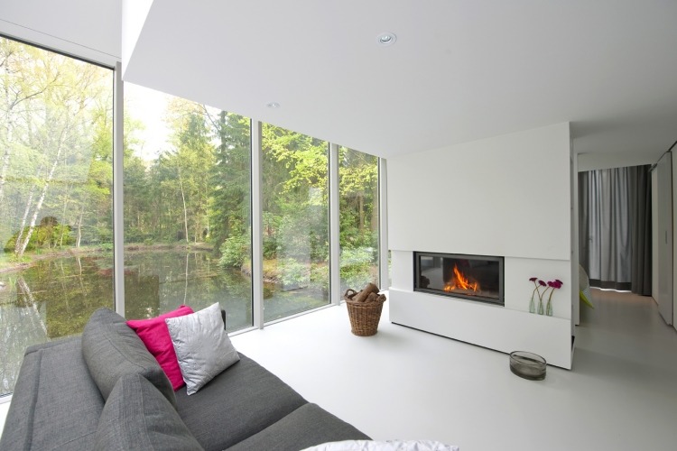 Kamin-modern-wohnzimmer-minimalistisch-weiss-panoramafenster-couch-korb-brennholz