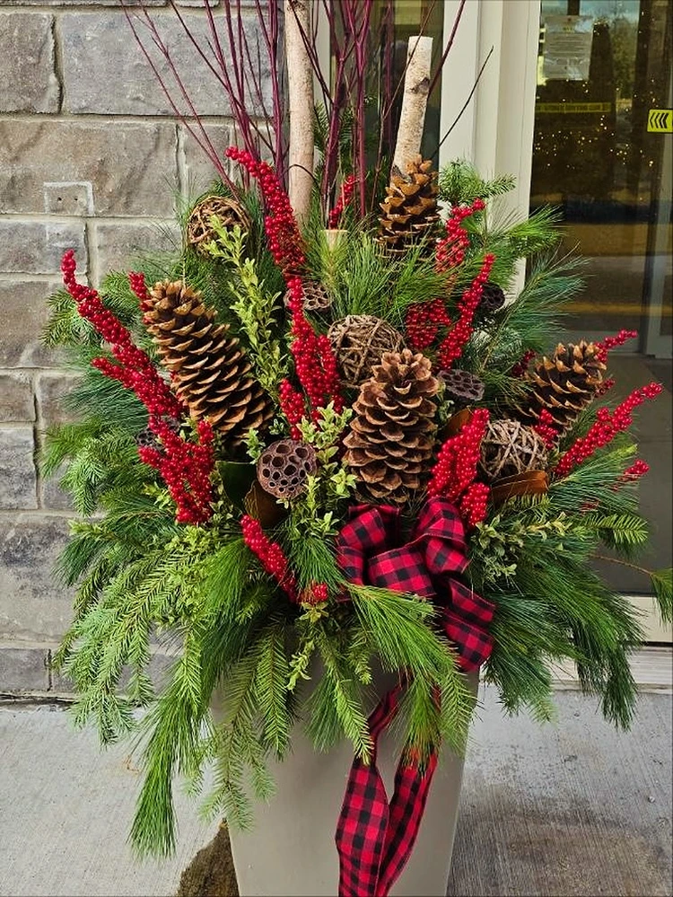 natürliches weihnachtsgesteck mit roten zweigen und großen zapfen