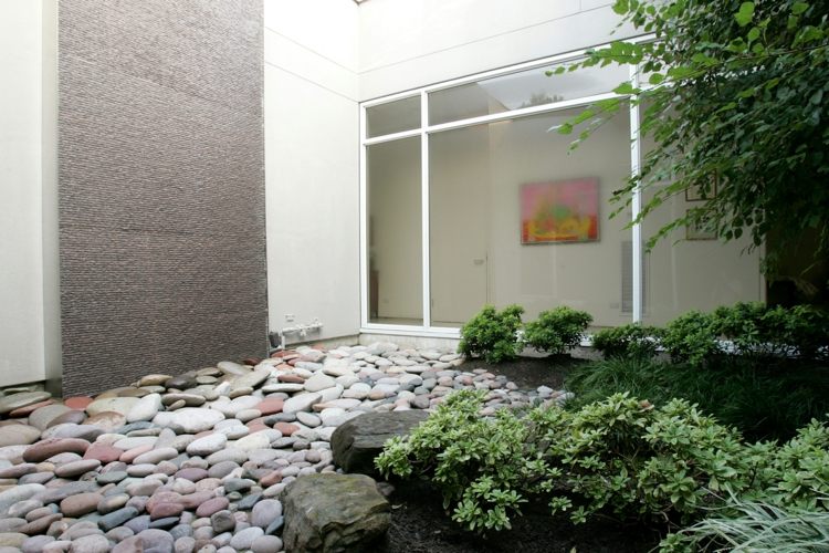 moderne-gartengestaltung-steinen-pflanzen-flusssteine-betonwand-fensterfront