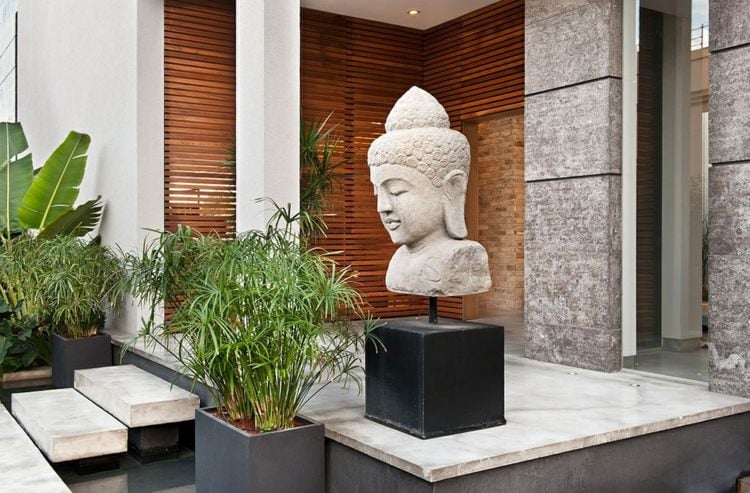 asiatische-gartendeko-buddha-statue-grau-stein-palmen-bananenstaude