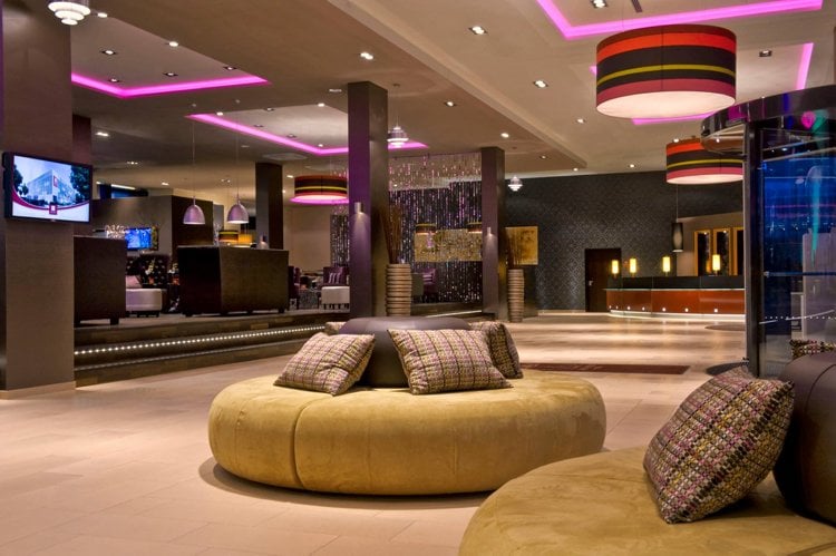 erstklassige raumkonzepte hotel-lobby-lila-deckenbeleuchtung-gelbe-runde-sitzgelegenheiten