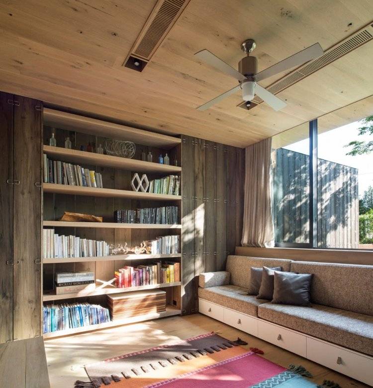 holzverkleidung-innen-aussen-minimalistisch-gästezimmer-bibliothekenwand-couch-fenster-groß