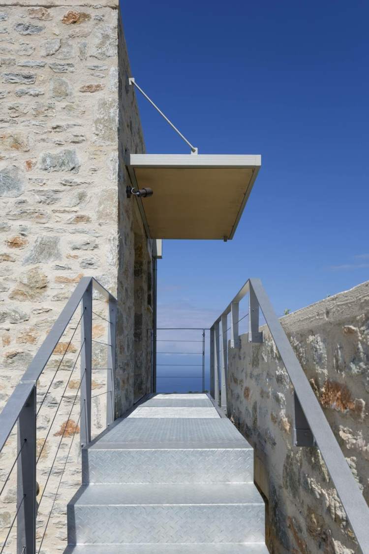 mediterrane-wand-stein-eingang-ueberdachung-modern-metall-treppe