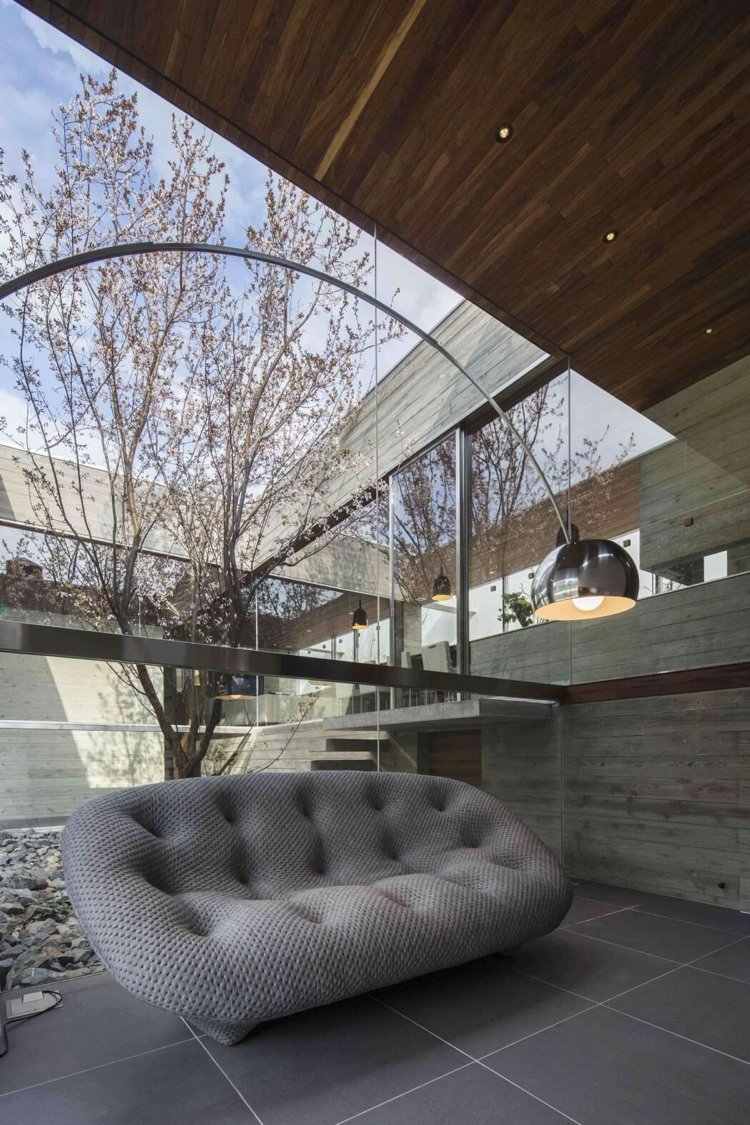 Panoramafenster zum Innengarten -minimalistisch-couch-stehlampe-beton-deckenverkleidung
