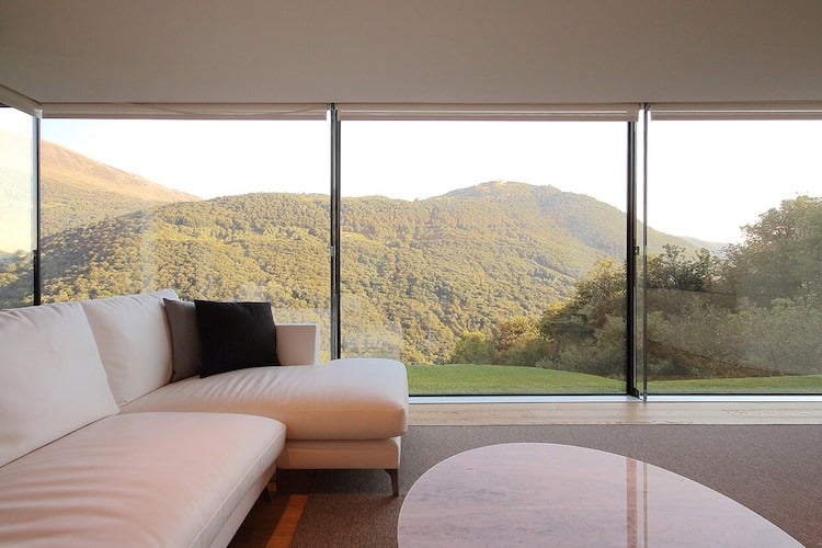 glasfassade-wohnzimmer-panoramafenster-couch-cremeweiss-moderne-einrichtung