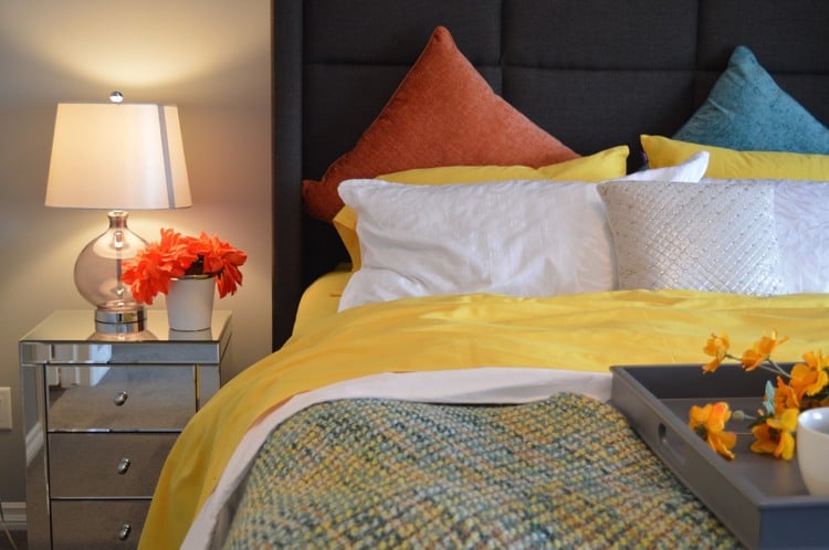 schlafzimmereinrichtung-bettwaesche-frische-farben-verspiegelter-nachtisch-schwarzes-gepolstertes-bett-kopfteil