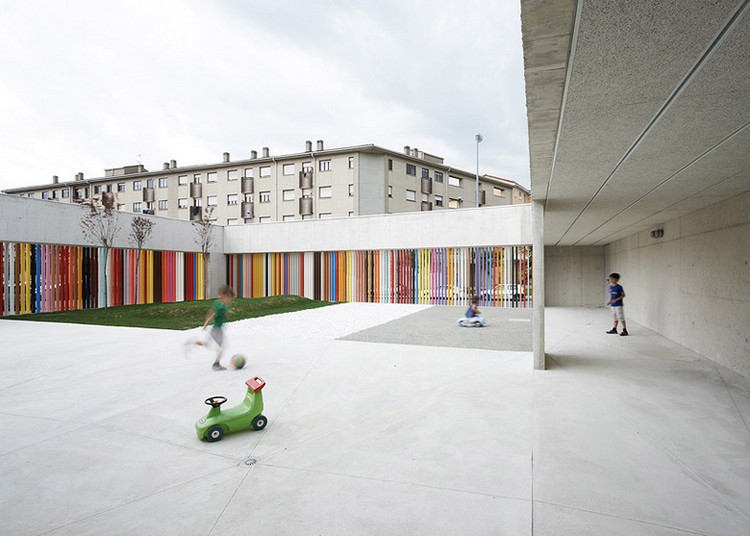 Kindergarten Architektur großer-innenhof-rasenfläche-farbenfrohe-fassade-beton