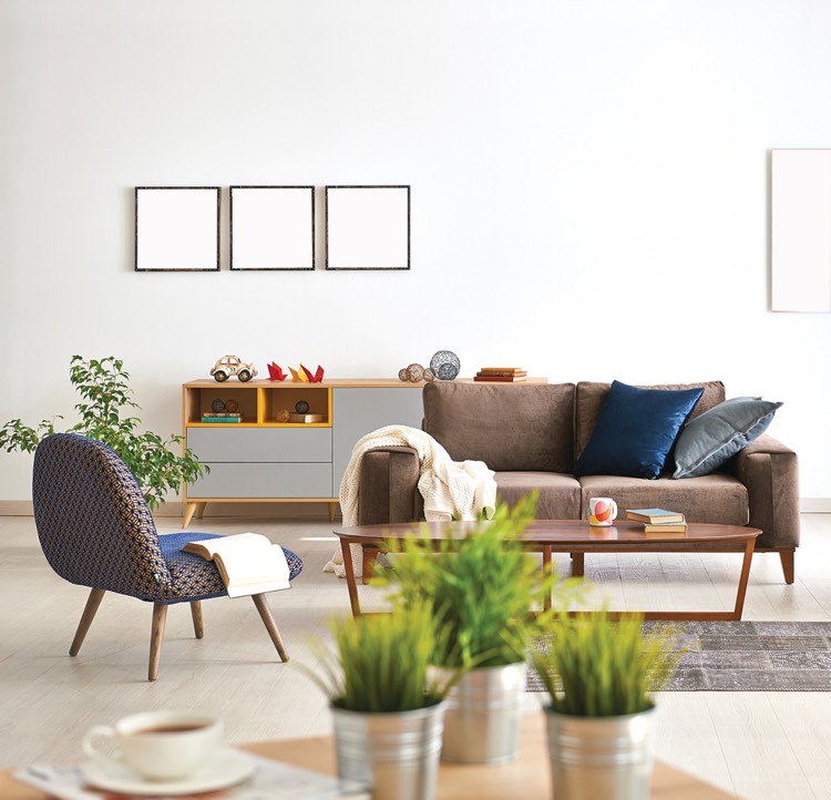 Eine elegant und spärlich eingerichtete Wohnung mit weißen Wänden, einer Couch, einem Couchtisch, einem Stuhl, Sideboard, Pflanzen und eine Tasse Kaffee im Vordergrund