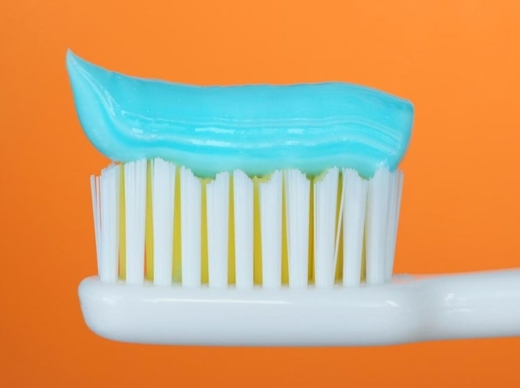 hausmittel-zahnschmerzen-zahnpasta-blau-zahnbürste-weiß-orange