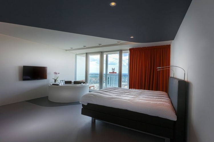 modern-wohnen-grautöne-schlafzimmer-whirlpool-fernseher-roter-farbakzent