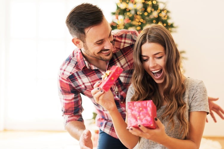 Mann überrascht seine Freundin mit einem Weihnachtsgeschenk