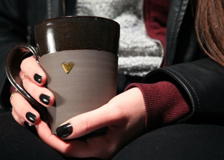 kaffeeflecken entfernen mädchen-kaffee-becher-schwarz-herz-halten-braun-gold-draußen-jacke-pullover