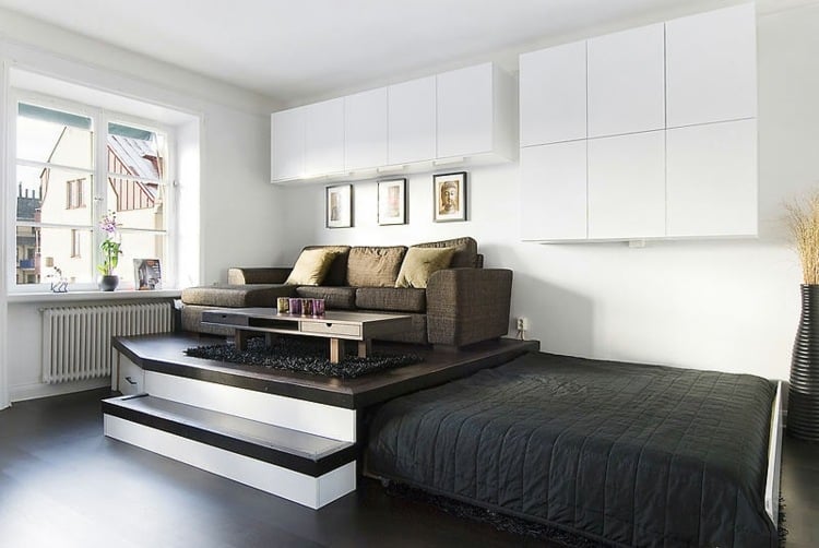 Idee für kleine Wohnzimmer - Sitzbereich mit Sofa auf einem Podest und Bett zum Ausziehen darunter