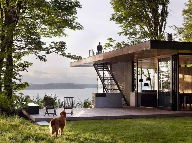 gartenhaus mit terrasse dachterrasse-treppen-aussicht-see-stühle-holzpodest-hund-mann-natur-bäume-pendelleuchten