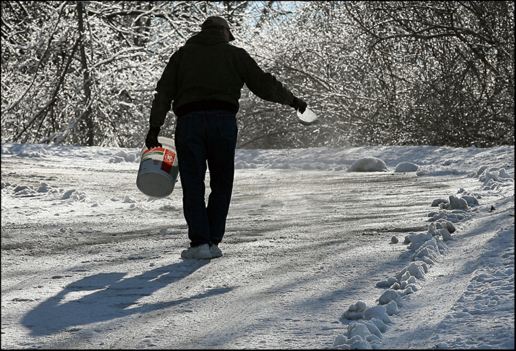 winterdienst-schneeräumen-mann-geheweg-bedeckt-rutschig-streuen-sand-kies-asche-eimer-schüssel.jpg