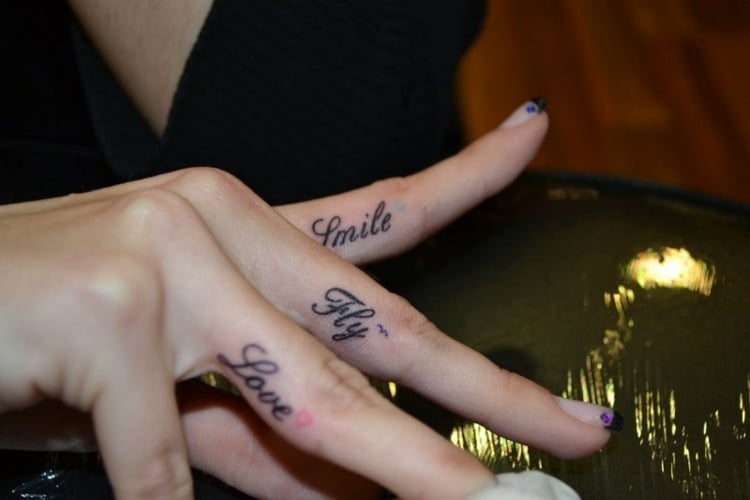 finger-tattoo-frauenhände-schriften-fingerinnenseite-herz-schwalbe-lächeln