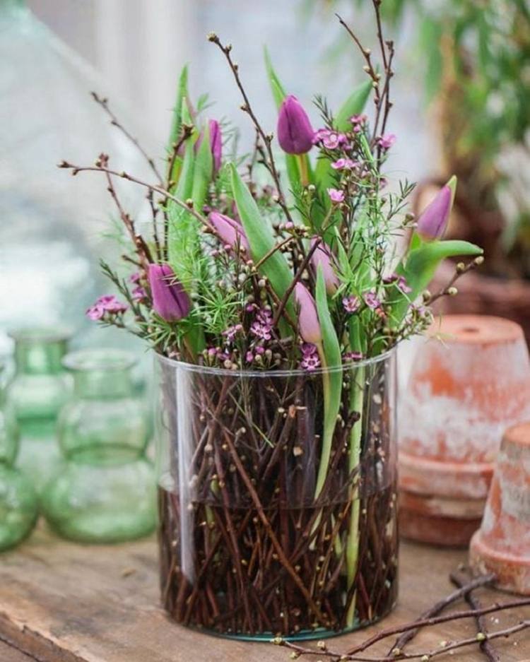 Großer Glasbehälter mit Tulpen und Zweigen als Alternative zum Blumenstrauß