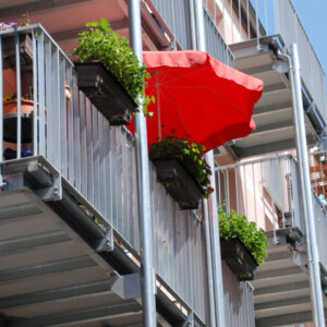 sonnenschirm-rot-balkon-blumenkasten-stahl-geländer