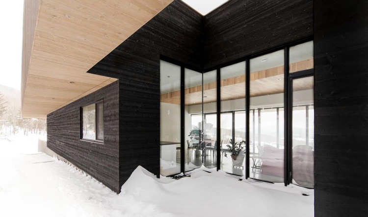 Fassade verkohltes Holz raumhohe Fenster Schnee