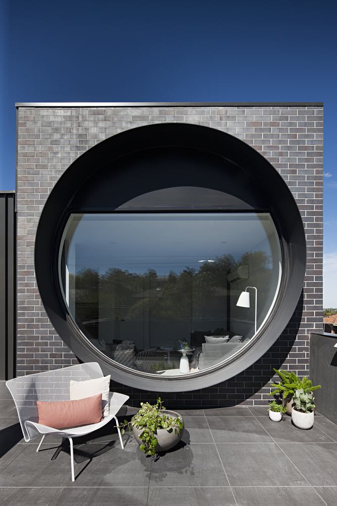 rundes Fenster Balkon schwarze Klinkerfassade