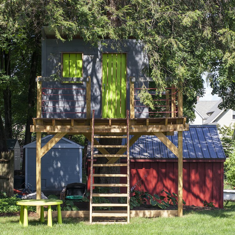 baumhaus für kinder im garten auf Stelzen grün grau fassade