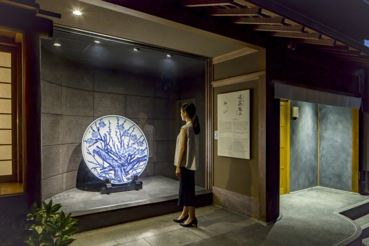 museumbesucher ausstellung traditionelle japanische keramik platte aprikosenbaum
