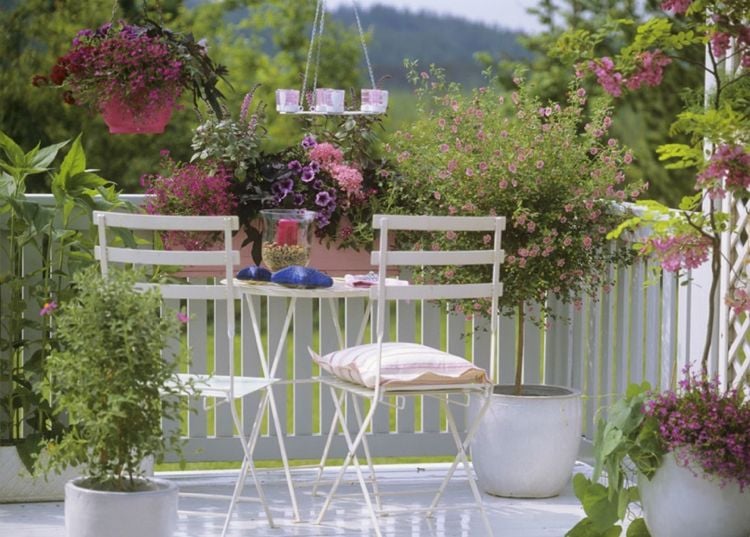 Balkon weiße Metallstühle rosa blühende Blumen